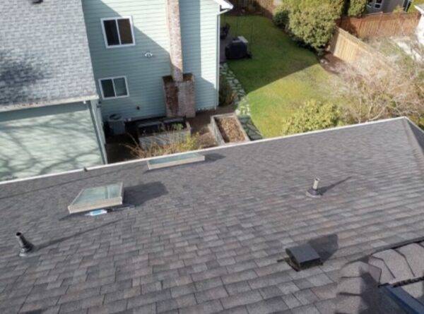 roofing shingles on a house with two skylights and a roof vent